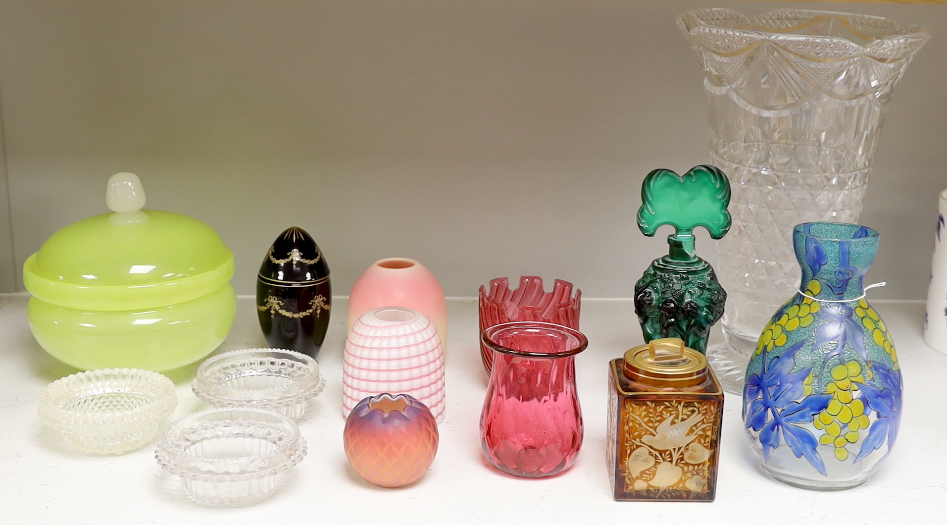 A quantity of various coloured and clear glass including an Art Deco figural scent bottle, cranberry glass vases and a yellow glass jar and cover, largest 30cm high